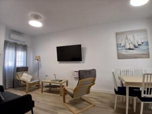 ein Wohnzimmer mit einem Tisch und einem TV an der Wand in der Unterkunft Casa Remo - Motril in Motril