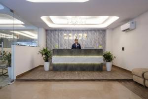 ein Mann steht an einem Rezeptionstresen in einer Lobby in der Unterkunft Leaf 9 Grand, Near Udyog vihar and Yashobhoomi in Gurgaon