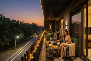 Ein Mann und eine Frau sitzen auf dem Balkon eines Gebäudes in der Unterkunft Leaf 9 Grand, Near Udyog vihar and Yashobhoomi in Gurgaon