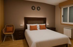 Un dormitorio con una cama grande y una silla. en CHALET A SOLO 5 MIN DE OURENSE CIUDAD con jardín y barbacoa, en Ourense