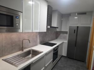 una cocina con fregadero y refrigerador en CHALET A SOLO 5 MIN DE OURENSE CIUDAD con jardín y barbacoa, en Ourense 10 fotos más