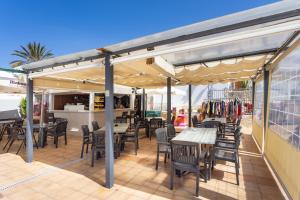 a patio with tables and chairs under a roof at New! Sea View Apartment with Aircon in Center of Las Americas in Playa de las Americas