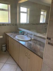a bathroom with a sink and a mirror at Hill Top Guesthouse in Plettenberg Bay