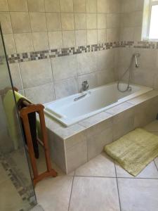 a bath tub in a bathroom with a sink at Hill Top Guesthouse in Plettenberg Bay
