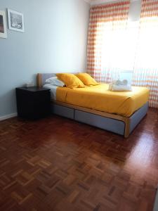 a bedroom with a bed with yellow sheets and a window at Cores do Tejo in Almada