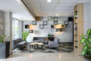 eine Lobby mit Sofas, einem Tisch und Pflanzen in der Unterkunft B&B Hotel Ljubljana Park in Ljubljana