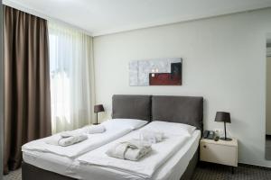 ein großes weißes Bett in einem Zimmer mit Fenster in der Unterkunft B&B Hotel Ljubljana Park in Ljubljana