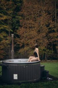 a woman sitting in a hot tub in a park at Babia Rest - całoroczny domek z balią z jacuzzi in Zawoja