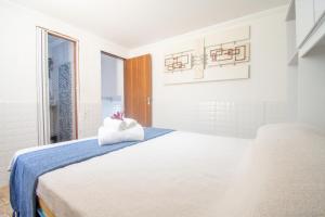 une chambre blanche avec un lit avec une serviette dessus dans l'établissement Pousada Vila Merced, à Búzios