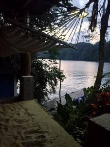 a hammock on a beach next to a body of water at casa colibri cañón de rio dulce in Lívingston +9 photos