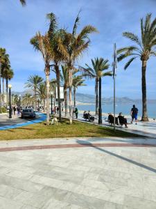 a park with palm trees and people sitting on benches at Albir Beach Apt in Albir