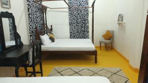 a room with a bed and a table and a chair at NOMAD Hostel Stone Town in Zanzibar City