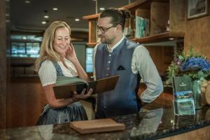 Ein Mann und eine Frau stehen mit einem Buch an einem Tresen in der Unterkunft Natur- und Sporthotel Zuflucht in Freudenstadt