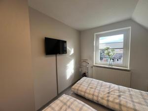 Ferienhaus Zum Gässchen في فايسنفلس: غرفة نوم بها سرير وتلفزيون على الحائط