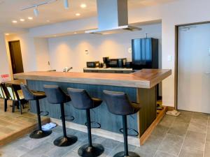 eine Küche mit einer Bar mit Hockern und einem Kühlschrank in der Unterkunft Rou in Nozawa Onsen + 15 Fotos