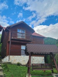 una casa di legno con una panchina di fronte di Casa Edimar a Sboghiţeşti