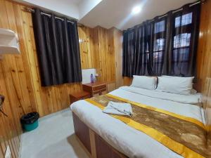 a bedroom with a large bed with wooden walls at Hotel Rashak in Gangtok +6 photos