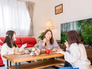 two girls sitting around a coffee table eating food at tazuraya-sakuramachi-一棟貸切-無料駐車場 in Takamatsu