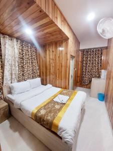 a large bed in a room with wooden walls at Hotel Rashak in Gangtok