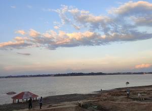 eine Gruppe von Menschen, die am Strand in der Nähe des Wassers stehen in der Unterkunft Veda hotel and home stay in Prayagraj