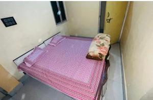 ein kleines Bett mit rosa Bettwäsche und einer Handtasche darauf in der Unterkunft Veda hotel and home stay in Prayagraj