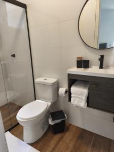 a white bathroom with a toilet and a mirror at Suíte privativa Vila Dom Pedro in Paraty