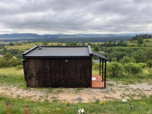 a wooden shed sitting on top of a field at Jurta I Sauna z widokiem na Tatry in Knurów