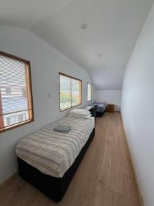 Qt inntouch في كوينزتاون: غرفة نوم بها سرير ونافذتين