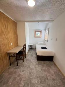 Qt inntouch في كوينزتاون: غرفة نوم بها سرير ومكتب وطاولة