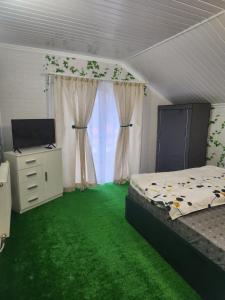 a bedroom with green carpet and a bed and a desk at Casa Edimar in Sboghiţeşti