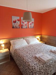 een slaapkamer met een bed met een oranje muur bij Home Iseo Lake in Bossico