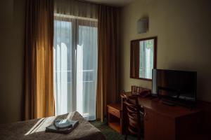 a hotel room with a bed and a tv and a window at Dionis Hotel in Varna City