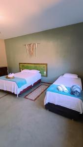 a bedroom with two beds and a window at Casa Frida 400m do centro - Serra do Cipo in Santana do Riacho +3 photos
