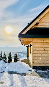 Cabaña de madera con árboles en la nieve en Tatra Village, en PyzÃ³wka