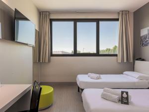 a room with three beds and a window at B&B HOTEL Bologna in Castel Maggiore