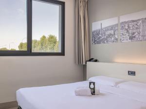 two beds in a room with a window at B&B HOTEL Bologna in Castel Maggiore +25 photos
