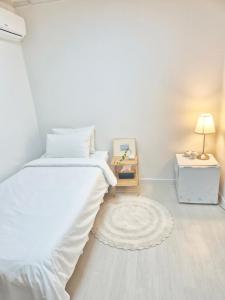 a white bedroom with a bed and a night stand at Blau Guesthouse in Gyeongju