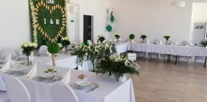 DługiePensjonat Długie Lubuskie的一间设有白色桌子和白色椅子及鲜花的房间