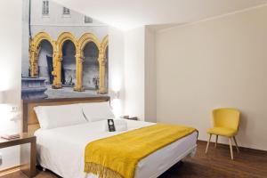 a bedroom with a bed and a yellow chair at B&B Hotel Palermo Quattro Canti in Palermo