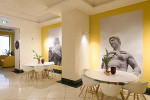 a room with two tables and a picture of a man on the wall at B&B Hotel Palermo Quattro Canti in Palermo