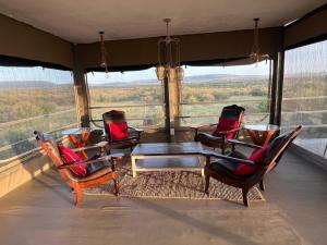 Mara SimbaKazuri mara camp的带阳台的带椅子和桌子的房间