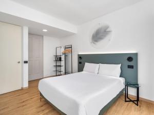 a bedroom with a large white bed and a ladder at B&B HOTEL Alba in Alba