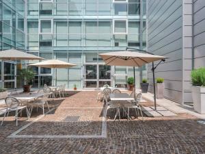 a patio with tables and umbrellas in front of a building at Park Hotel Cassano in Cassano dʼAdda