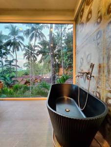 a black bath tub in a room with a window at Tranquill riverview resort by trideus-Saipem, Candolim in Candolim