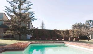 a swimming pool in front of a house with a tree at La Curia in Pontevedra