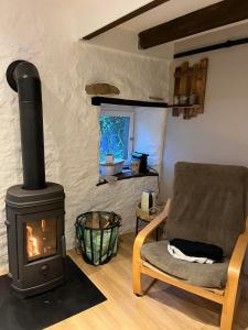 a living room with a wood stove and a chair at "Le Cabanon" chambre d'hôte in Avioth +1 photo