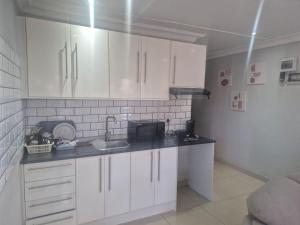 Una cocina con gabinetes blancos y un fregadero. en Maglovir Economy, en Tiervlei