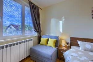 ein Schlafzimmer mit einem Bett und einem Stuhl und einem Fenster in der Unterkunft Rila North Samokov in Samokow