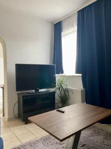 韦尔策Gemütliche 2 Zimmer Ferienwohnung mit Terrasse Fernsehsessel Spülmaschine Grill Schaukel, fußläufig zu S-Bahn nach München und See, ideal zum Entspannen aber auch zum Arbeiten的配有平板电视和桌子的客厅