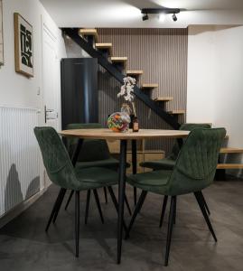 ein Esstisch mit grünen Stühlen und eine Treppe in der Unterkunft La charmante maison Cosy à Saint-Avold in Saint-Avold